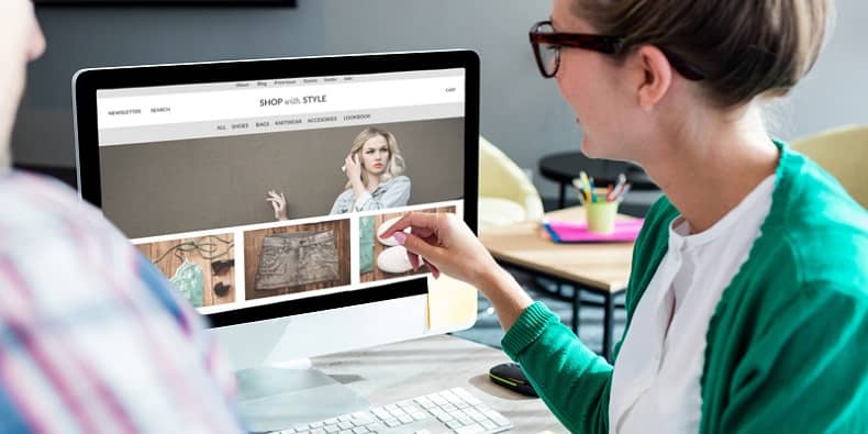 Female in green cardigan works on a website at her Mac computer