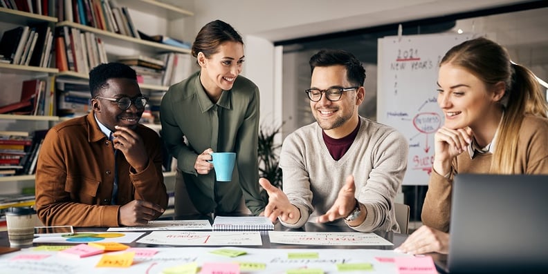 two men and two women in an office looking at colourful post-it notes on a table