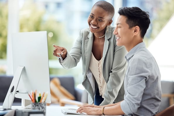 Smiling man and woman looking at a computer desktop screen in a light and airy office 