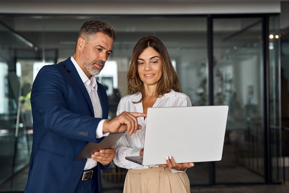 man and women in office looking at laptop