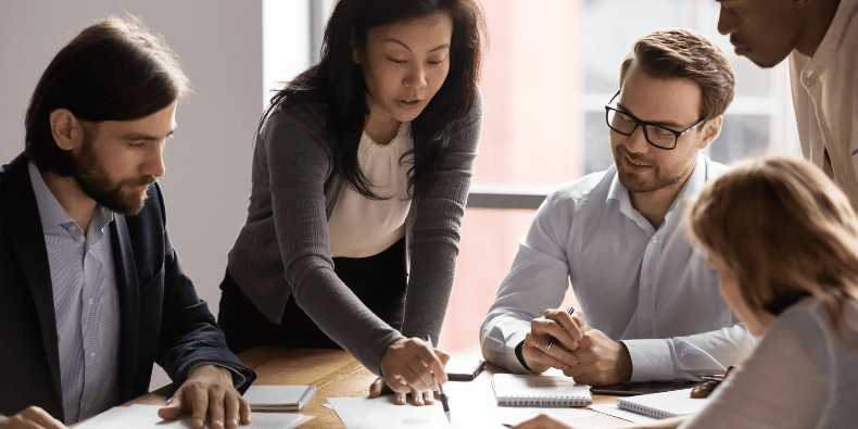 Diverse team sat around a desk discussing a recent competitor analysis